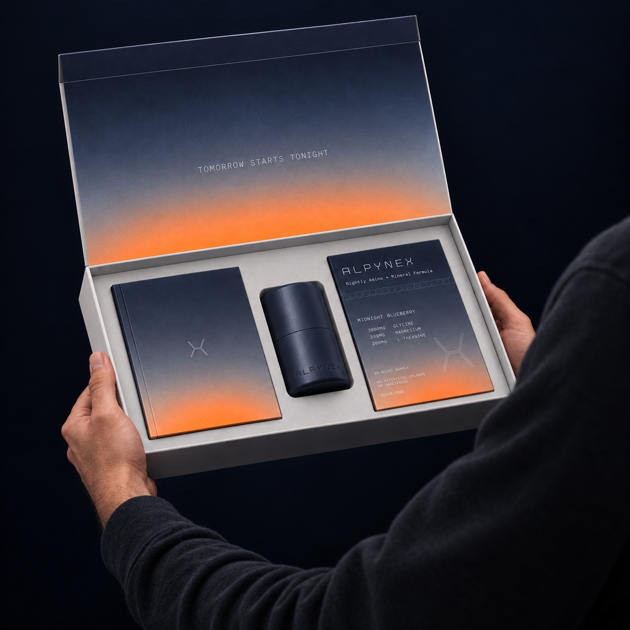 The open ALPYNEX starter kit held in two hands, with its book, reusable tin and Midnight Blueberry refill